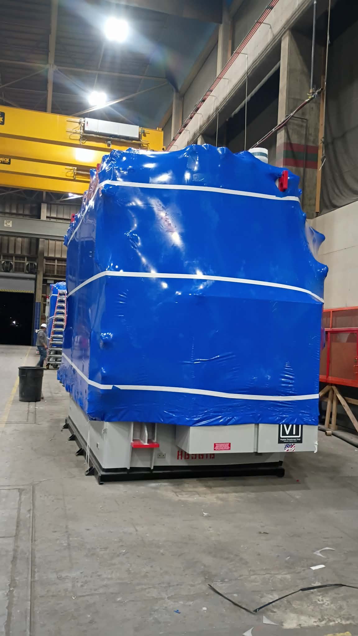 Wrapped industrial transformer in warehouse staging area